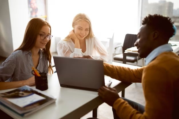 Un étudiant montre son écran d'ordinateur à 2 étudiantes